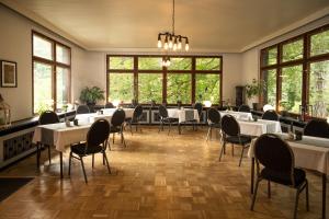 a dining room with tables and chairs and windows at Hotel Mühlental in Wernigerode