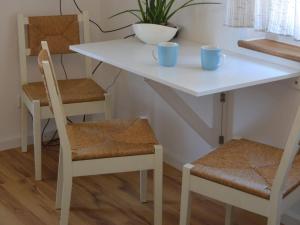 Una mesa blanca y sillas con dos tazas. en Ferienwohnung Wanderglück, en Mössingen