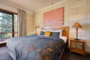 a bedroom with a large bed and a balcony at Loch Ard Motor Inn in Port Campbell