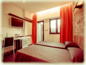 カステル・ディ・レバにあるオール ウェイズ ガーデン ホテル ＆ レジャーのベッドルーム1室(赤いカーテン付きのベッド1台、デスク付)