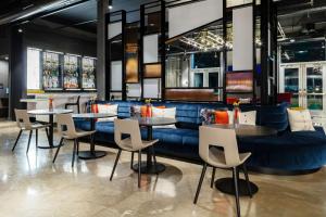 a restaurant with tables and chairs and a blue couch at Aloft Dallas Arlington South in Arlington