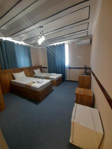 2 camas en una habitación con cortinas azules en Hotel Al Hayit Teracce, en Bukhara