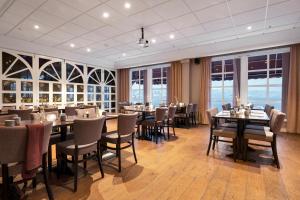 a dining room with tables and chairs and windows at Clarion Hotel Tyholmen in Arendal