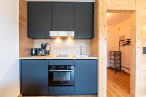 a kitchen with black cabinets and a blue oven at Le Balcon du Mont Blanc - Studio refait à neuf in Cordon