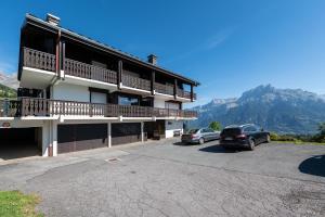 a building with two cars parked in a parking lot at Le Balcon du Mont Blanc - Studio refait à neuf in Cordon