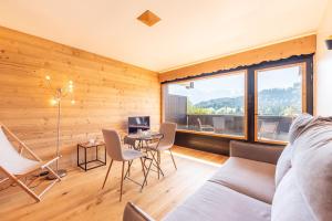 a living room with a couch and a table with chairs at Le Balcon du Mont Blanc - Studio refait à neuf in Cordon