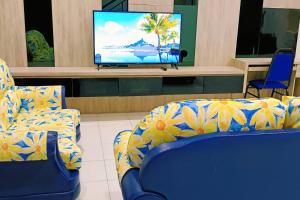 sala de estar con 2 sillas azules y TV de pantalla plana en kulai2story 5R24pax nearJPO/JB airport ioiMall Aeon, en Kulai