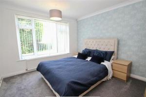 1 dormitorio con cama con sábanas azules y ventana en Full Modern Home - short & long stays, 