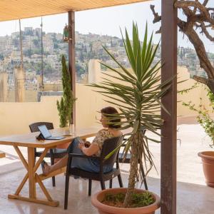 una mujer sentada en una mesa con un portátil en Villa Mira Guesthouse - Downtown Central Amman - AL DIYRIH, en Amán