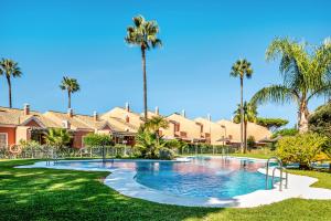 a resort pool with palm trees in the background at Ático Novo Sancti in Chiclana de la Frontera
