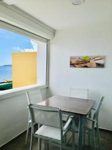 uma sala de jantar com uma mesa e cadeiras e uma janela em L'heure Dorée - Charmant appartement vue mer em Saint-Pierre