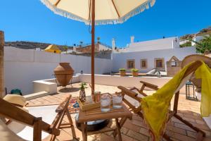 patio ze stołem, krzesłami i parasolem w obiekcie Evangelia's Traditional Villa Lindos w Líndos +25 zdjęć
