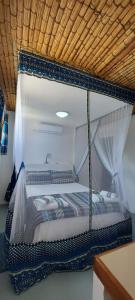 Cette chambre comprend un lit à baldaquin. dans l'établissement Neptune's Lodge and Beach Bar, à Cabo Nhamua