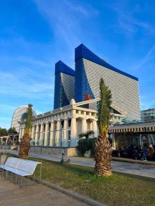 a building with two palm trees in front of it at Elegance Sea View Aparthotel In Orbi City Batumi in Batumi