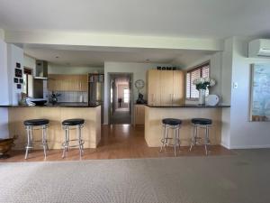 a kitchen with three bar stools and a counter at Secluded Bays Home in Auckland