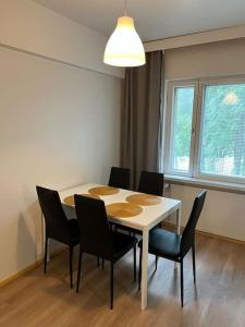 mesa de comedor con sillas y lámpara en Kotimaailma - Valoisa Kolmio Vantaalla, en Vantaa
