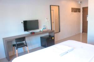 1 dormitorio con 1 cama y escritorio con TV en ประทายบุรี โฮเทล แอนด์ รีสอร์ท en Ban Wang Muang