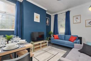 a living room with blue walls and a blue couch at Spacious 3-Bedroom House With Garden and Parking in Stockton-on-Tees