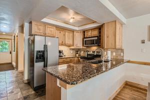 a kitchen with wooden cabinets and a stainless steel refrigerator at NEW LISTING!! Breck Mountain Magic condo in Breckenridge