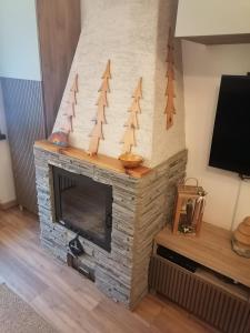 a living room with a stone fireplace with trees on it at Casa Flippola - Trilocale Santa Caterina Centro Paese in Santa Caterina Valfurva