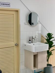 ein Badezimmer mit einem weißen Waschbecken und einem Spiegel in der Unterkunft Marni BKK Hostel in Bangkok