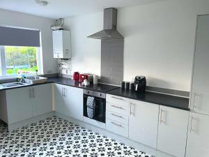 a kitchen with white cabinets and a black and white tile floor at 4-bedroom home with off-road parking in Swansea