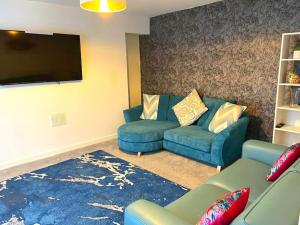 een woonkamer met een blauwe bank en een flatscreen-tv bij 4-bedroom home with off-road parking in Swansea