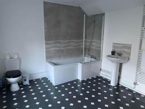 a bathroom with a tub and a toilet and a sink at 4-bedroom home with off-road parking in Swansea