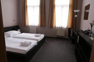 a hotel room with two beds with towels on them at Hotel Zlatá Štika in Pardubice