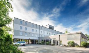 un bâtiment avec une voiture garée devant lui dans l'établissement Median Hotel Hannover Messe, à Hanovre