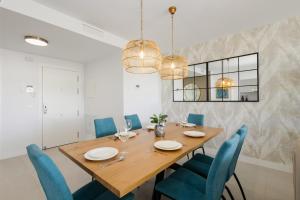 une salle à manger avec une table en bois et des chaises bleues dans l'établissement Magnificent apartment, close to the beach, in Estepona, à Estepona