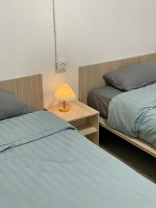 a bedroom with two beds and a table with a lamp at Marni BKK Hostel in Bangkok