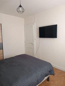 um quarto com uma cama e uma televisão de ecrã plano em Maison avec jardin em Issoudun