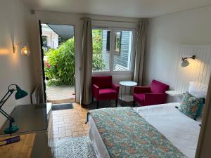 a bedroom with a bed and two chairs and a window at Hôtel Monet in Honfleur
