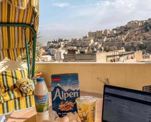 a laptop on a table with a view of a city at Villa Mira Guesthouse - Downtown Central Amman - AL DIYRIH in Amman