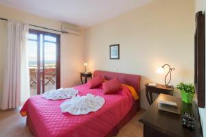a bedroom with a bed with a pink bedspread and a table at Villa Persephone by PosarelliVillas in Plaka