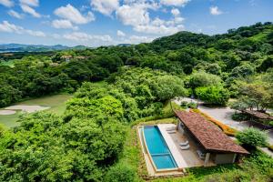 孔查海灘的住宿－Roble Sabana 404 Luxury Apartment Adults Only - Reserva Conchal，享有带游泳池和树木的房屋的空中景致