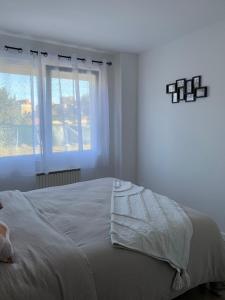 a white bedroom with a bed and a window at Chez Claudine APPART COSY in Château-Gontier