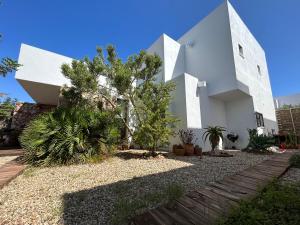 ein weißes Haus mit Bäumen und Pflanzen im Hof in der Unterkunft CASA GRANADO en Cabo de Gata in Rodalquilar