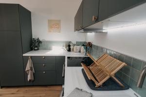 a kitchen with green cabinets and a wooden chair at Grange Petite Brise bord de mer in Luc-sur-Mer
