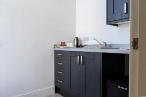 a kitchen with black cabinets and a sink at The Sandbeck, Ruswarp in Whitby