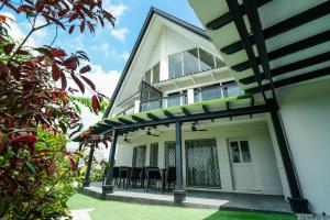 Casa blanca con porche con sillas negras en Jacobs Hill Tagaytay, en Tagaytay