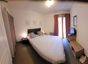a bedroom with a large white bed and a television at T2 pic de l’ours Fontromeu in Font-Romeu