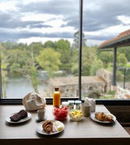 - une table avec des aliments pour le petit-déjeuner et une vue sur une fenêtre dans l'établissement Casa do Engenho Braga, à Braga