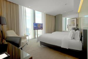 a hotel room with a bed and a chair and window at Amman Rotana in Amman +106 photos
