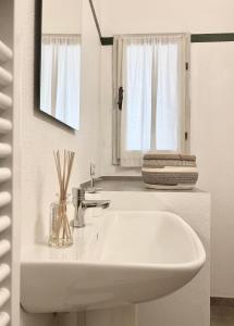 a white bathroom with a sink and a mirror at Alloggio 1 / Casa Marley Porto Pollo in Barrabisa +16 photos