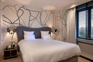 - une chambre avec un grand lit blanc orné d'une peinture murale dans l'établissement Hotel Groenendaal, à Hoeilaart