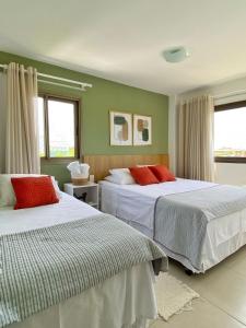 two beds in a room with green walls and windows at O Paraíso que você merece in Praia do Forte
