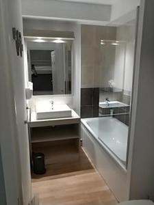 a bathroom with two sinks and a tub and a mirror at studio montagne in Les Orres