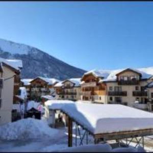 a snow covered building with a mountain in the background at studio montagne in Les Orres